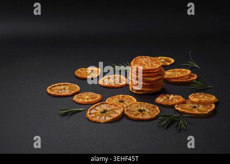 Food, Dried round shape slices of bright orange color tangerine on a dark textural background Stock Photo