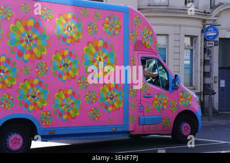 Vibrant pink van completely covered in colourful psychedelic flower patterns parked on a street in Brighton, England, creating a cheerful and eye-catc Stock Photo