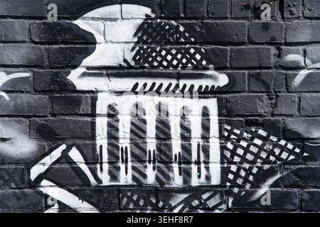 Bold black and white street art mural of a classical monument with columns and checkered patterns on a dark brick wall in Brighton, England. Stock Photo