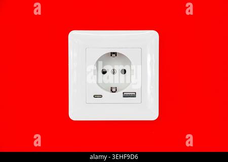 electric white socket on the red wall close-up Stock Photo