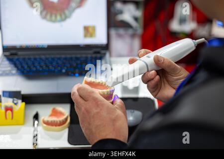 Dental Technician Scanning Tooth Model. Close-up of a dental technician using a digital scanner on a teeth model for modern dental design and Stock Photo