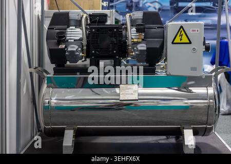 Stainless Steel Industrial Air Compressor Unit. Front view of a stainless steel air compressor with motor, control box, warning sign, and polished Stock Photo