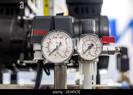 Air Compressor Pressure Gauges Close Up. Close-up of pressure gauges and control components on an industrial air compressor used for dental or medical Stock Photo