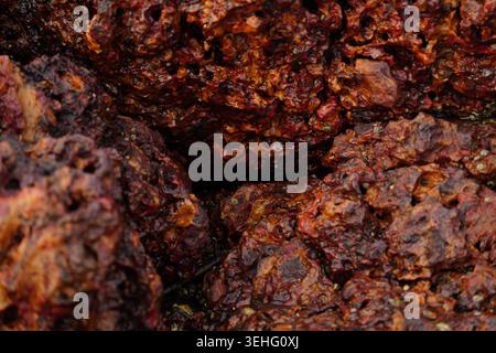 Abstract close-up of porous rust colored rock texture with natural geological patterns Stock Photo