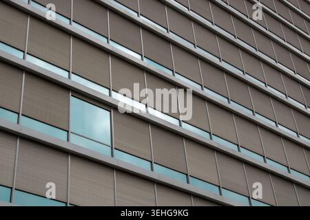 Exterior glass facade of a contemporary office building featuring geometric patterns and shades Stock Photo