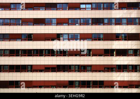 Building facade presenting an urban architecture pattern of uniform windows and red blinds Stock Photo