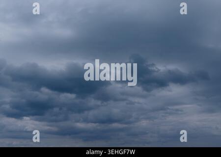 Dark clouds fill the sky, creating a moody scene over a wide landscape, suggesting possible rain or stormy weather approaching Stock Photo