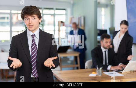 Young man stands against the background of the interior of a modern office Stock Photo