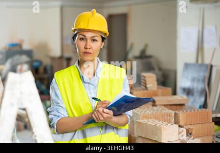 Woman making notes on indoor construction site Stock Photo