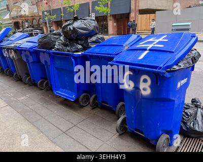 Recycling bins on a city sidewalk, filled with black trash bags. Toronto, Ontario, Canada Stock Photo