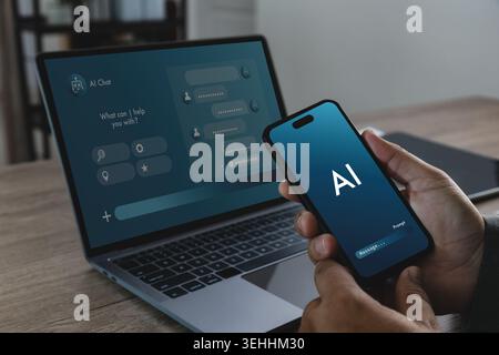 Hand holding smartphone with AI chatbot interface beside laptop displaying search assistant dashboard, suitable for artificial intelligence prompt, we Stock Photo