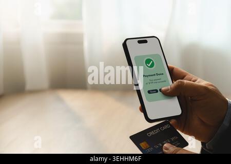 Hand holding smartphone with completed mobile payment transaction and credit card during online banking process for digital finance, banking, transfer Stock Photo
