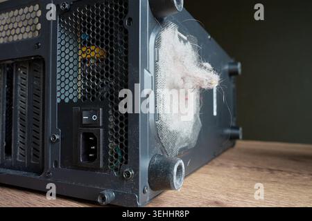 Dust and lint clog mesh vent on back of desktop computer case. PC maintenance, cleaning, airflow and overheating prevention concept Stock Photo