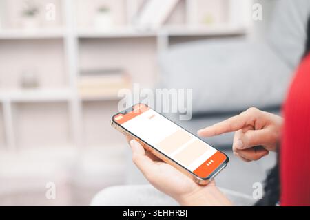 Closeup of young Asian woman using smartphone app for online shopping at home, browsing ecommerce interface on mobile screen, digital lifestyle, finte Stock Photo