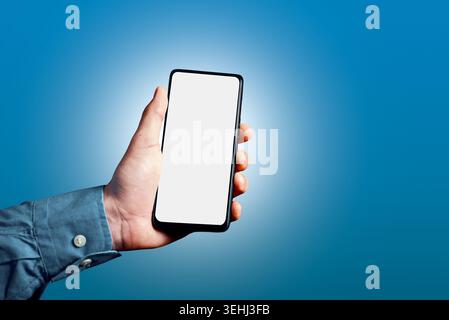 Hand holding modern smartphone with blank white screen for content. Concept of mobile communication, social media, app display Stock Photo