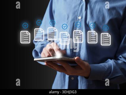 Businessperson using a tablet for document review and task management, ensuring compliance with digital checklists and verification Stock Photo
