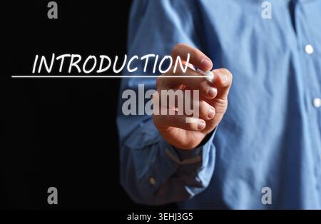 Businessman hand interacting with a glowing introduction word and underline on a black background, representing new beginnings Stock Photo