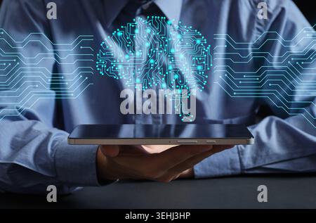 Person holding a tablet displaying a circuit board shaped like a human brain, symbolizing AI, machine learning, neural network and digital innovation Stock Photo