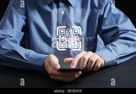 Person holding a smartphone, scanning a glowing virtual QR code for digital payment, information, or mobile technology access Stock Photo