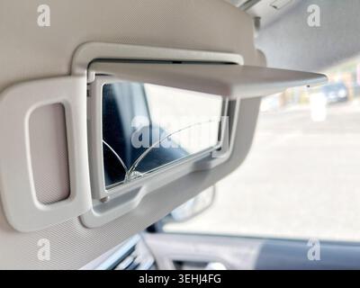 Damaged vanity mirror with visible crack mounted inside a folded car sun visor Stock Photo
