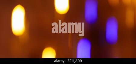 Defocused bokeh lights with warm orange and blue glow on a dark background for festive design Stock Photo