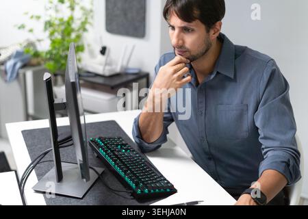 Latino Professional Thinking While Working At Computer In Modern Office Stock Photo