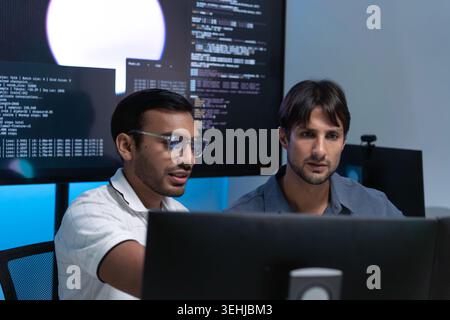 Software Developers Discussing AI Code On Computers In Tech Office Stock Photo