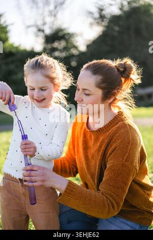 Mother and child blowing bubbles in sunlight Stock Photo
