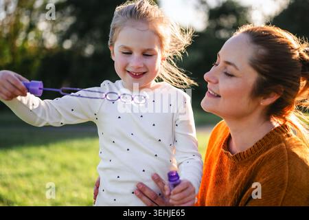 Mother and child blowing bubbles in sunlight Stock Photo