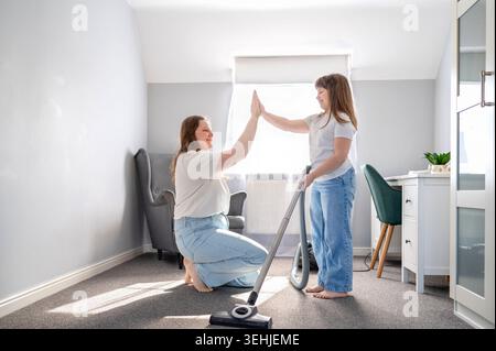 Mother and daughter giving high five during house cleaning at home Stock Photo