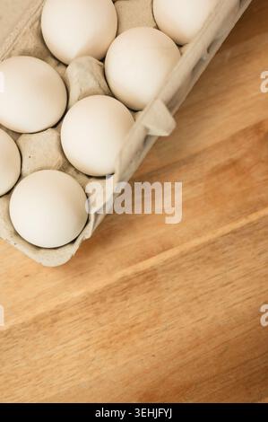 Close-up of white eggs in carton on wooden table with copy space Stock Photo