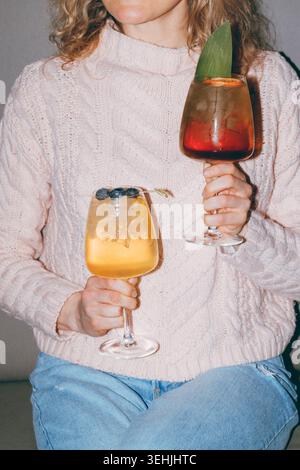 Girl holding 2 cocktails in her hands. Flash, film effect Stock Photo