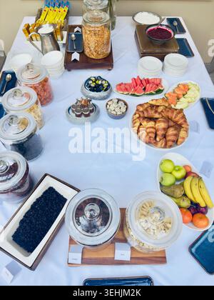 Selection of breakfast foods including croissants, fresh fruit, cereals and preserves displayed on a buffet table Stock Photo