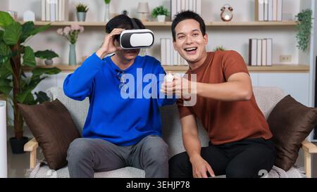 Asian senior man experiencing virtual reality with young man at home Stock Photo