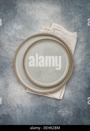 empty grey plates and linen napkin on grey concrete or stone table. Cooking background. Rustic style. Selective focus. Top view, copy space Stock Photo