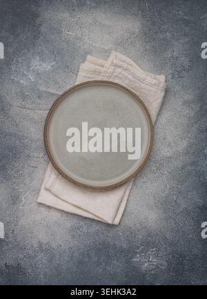 empty grey plate and linen napkin on grey concrete or stone table. Cooking background. Rustic style. Selective focus. Top view, copy space Stock Photo