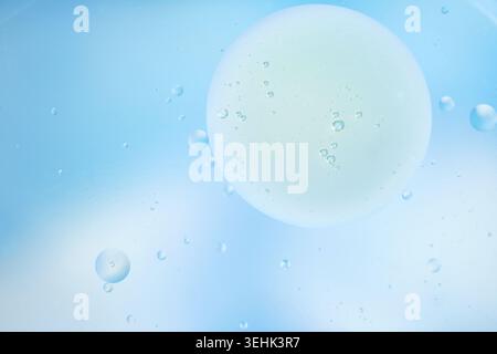 Minimal macro composition with delicate bubbles in pale blue liquid and a soft circular highlight. Stock Photo