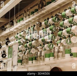 Green mugs and kitchen accessories arranged on wall shelves inside IKEA store. Belgrade, Serbia - May 12, 2026. Stock Photo