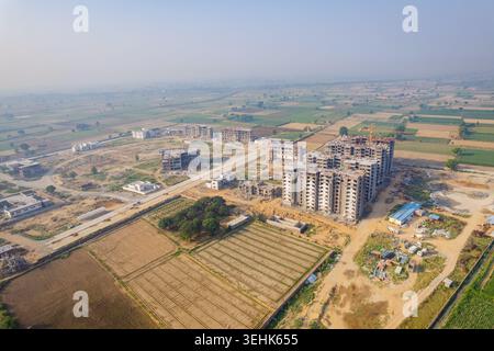 Aerial view of modern residential apartment buildings under construction surrounded by vast agricultural fields and rural landscape under a clear hazy Stock Photo
