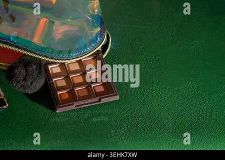 Eyeshadow brown Palette and Makeup with Iridescent Bag Close-up. Beauty Products Cosmetic on Green background. Stock Photo