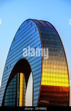 Close-up of the Crescent Hotel's curved glass facade reflecting warm sunset light. Baku, Azerbaijan. Stock Photo
