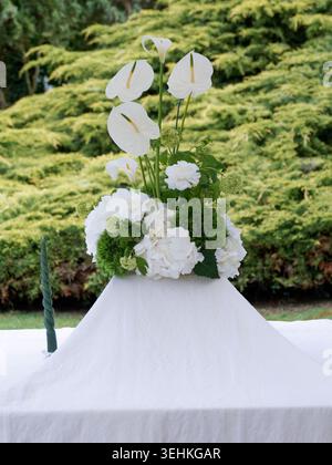 Elegant floral arrangement with white and green flowers placed on a table for an outdoor ceremony in France. Stock Photo
