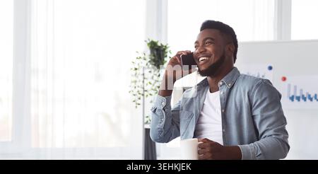Black worker calling to friends during working hours in office Stock Photo