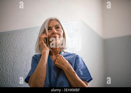 Tired nurse taking break during hospital shift, calling with family. Stock Photo