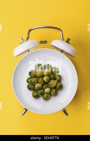 Food, Boiled Brussels sprouts as a vegetarian side dish for lunch. Breakfast as a plate concept instead of a dial on a vintage alarm clock Stock Photo