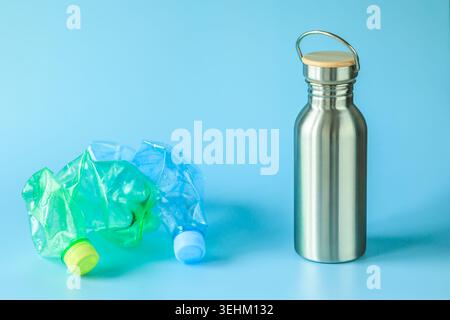 Reusable stainless steel water bottle and crushed plastic bottles on blue background, eco concept of reducing single-use plastic, recycling and sustai Stock Photo