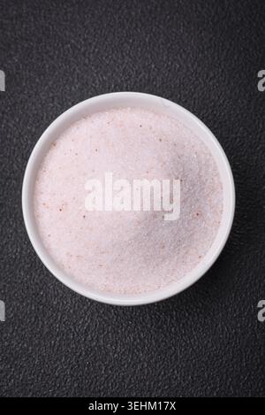 Food, Fine pink Himalayan table salt in a ceramic bowl on a dark concrete background Stock Photo