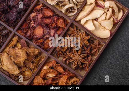 Food, Variation of dry fruits strawberry, apple, cherry, banana, peach, plum and star anise in a box on a dark concrete background Stock Photo