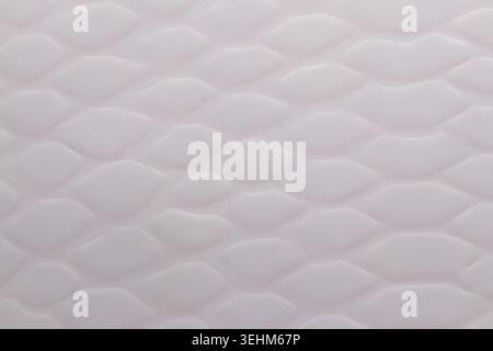 Macro shot of light pink or white textured surface with embossed scale pattern. Close up abstract background of faux snake skin, geometric cellular le Stock Photo