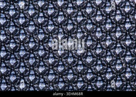 Macro shot of black synthetic mesh fabric with blue undertone. Top view of breathable textile net structure, detailed fiber backdrop for sportswear, s Stock Photo